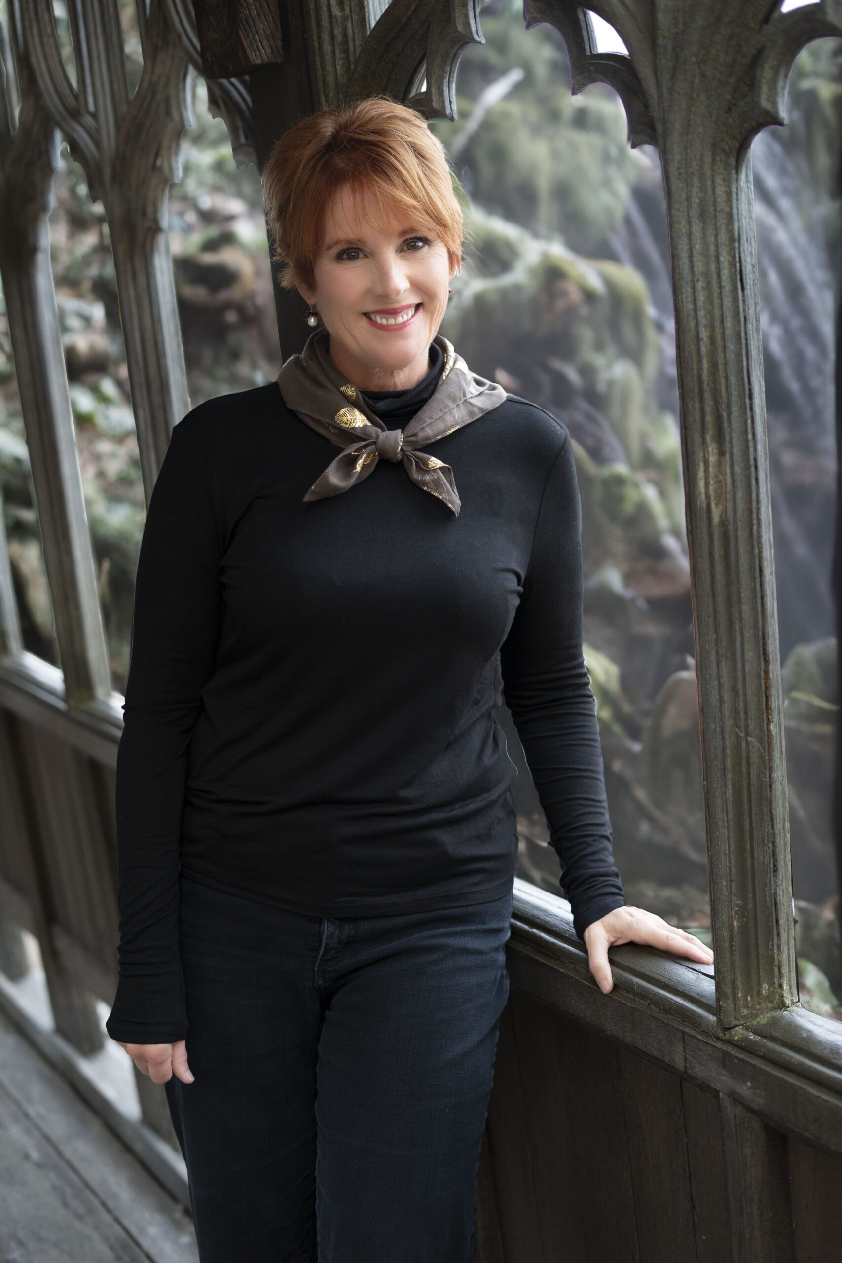 Pat standing at a bridge with a waterfall behind her.