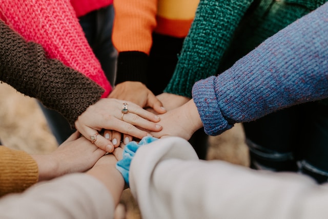 Eight people's hands joining together.