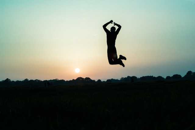 Person jumping up in the air against the horizon.